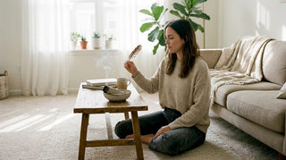 Im Wohnzimmer verteilt eine Frau behutsam Rauch mit einer Räucherquelle.
