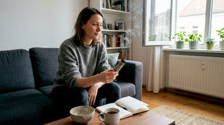 Eine Frau räuchert im Wohnzimmer und genießt die entspannte Atmosphäre.