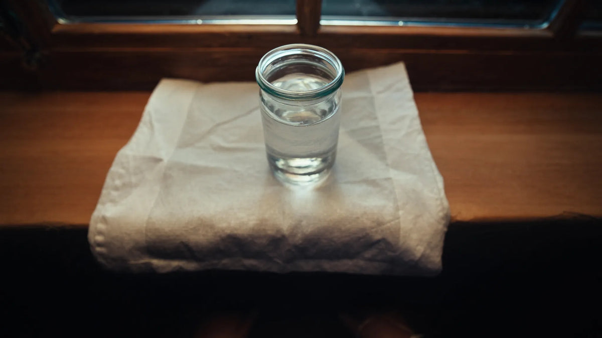 Glasgefäß mit Mondwasser auf Fensterbank im Mondlicht