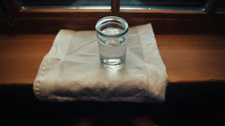 Glasgefäß mit Mondwasser auf Fensterbank im Mondlicht